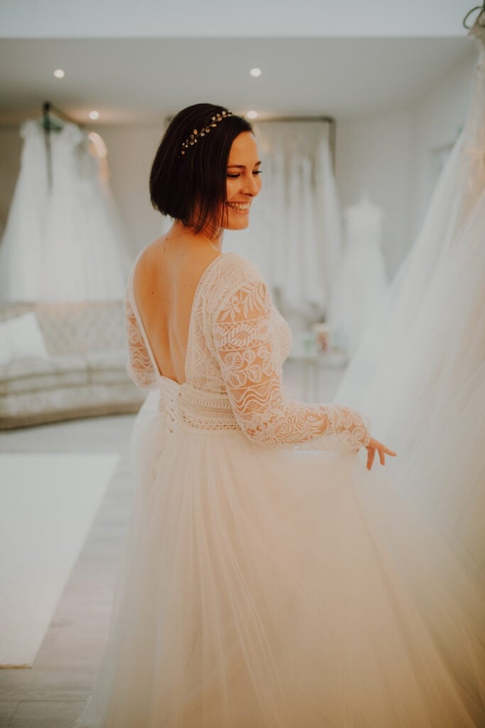 Lena hilft einer Braut, ein Hochzeitskleid anzuprobieren